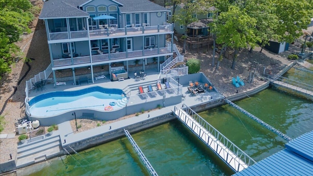Un bâtiment à deux étages doté d’une piscine et d’une jetée qui s’avance sur une étendue d’eau.