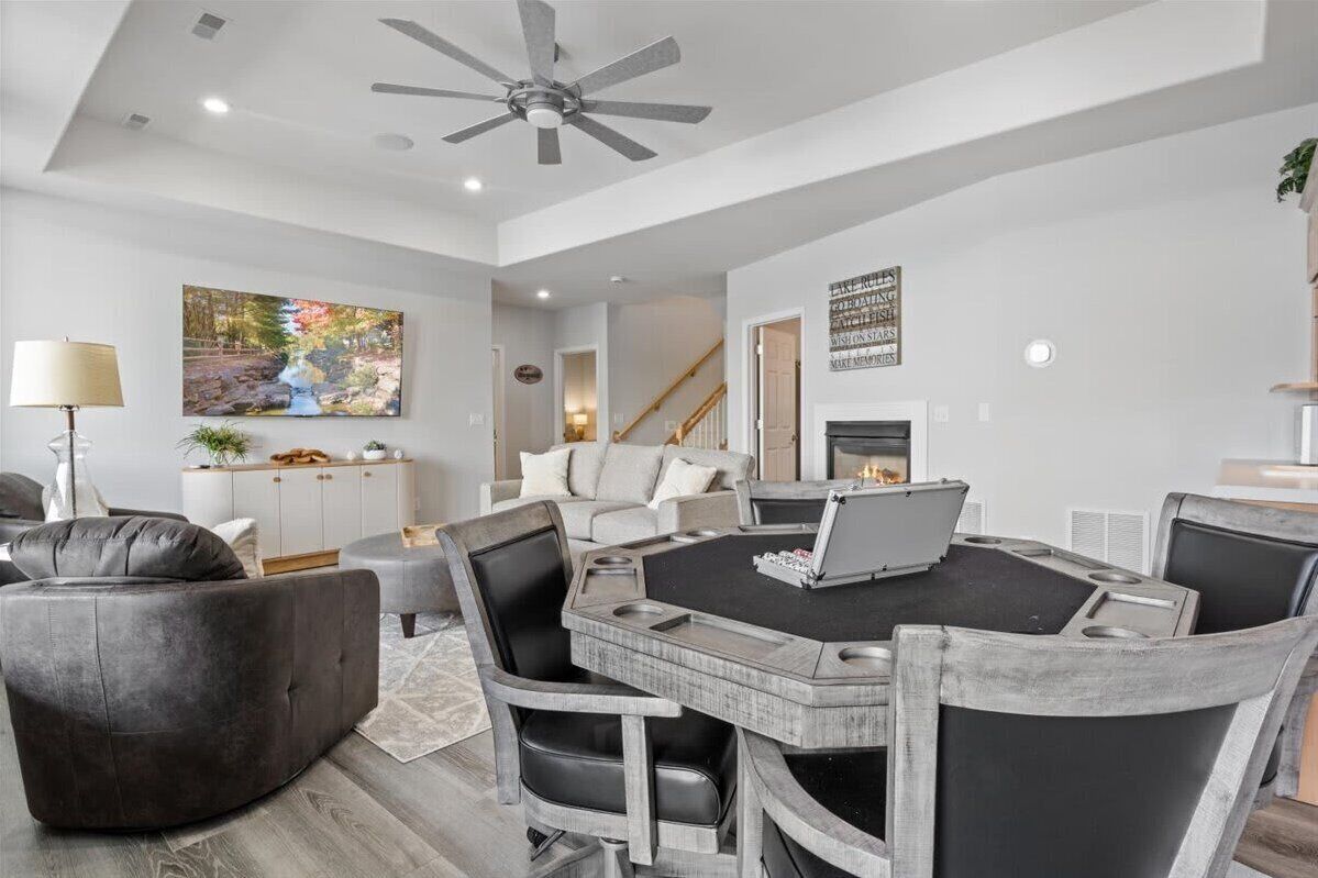 A modern living room with a round coffee table, grey upholstered chairs, a sofa, and a ceiling fan.