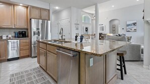 Une cuisine moderne dotée d’appareils électroménagers en acier inoxydable, d’un plan de travail en granit et de meubles en bois.