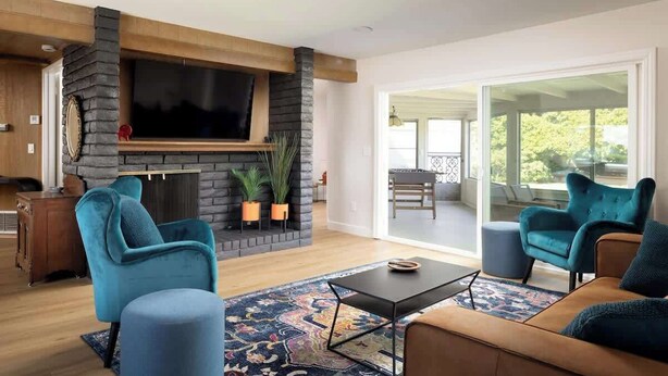 Een moderne woonkamer met een stenen open haard, een flatscreen televisie en comfortabele zithoek.
