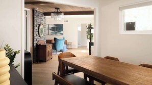 Een eetgedeelte met een houten tafel en stoelen, een accentmuur van steen en een kroonluchter.
