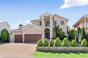 Stunning two-story home with a central entrance and beautifully manicured grounds.