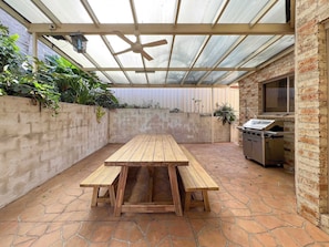 Enjoy al fresco dining on the patio with a grill, ceiling fan, and comfortable seating.