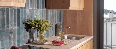 A modern kitchen with wooden cabinetry, a tiled backsplash, and a view of the city through a large window.