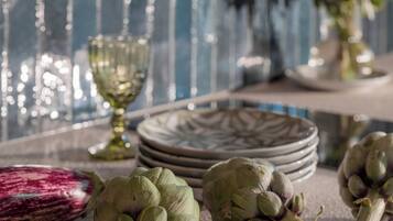 A dining table with plates, a glass, and artichokes.