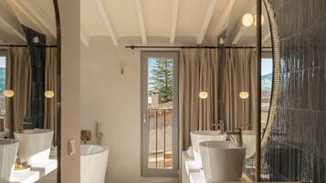 Un baño moderno con un espejo grande, dos lavamanos, una bañera y vistas al exterior a través de una puerta de cristal.