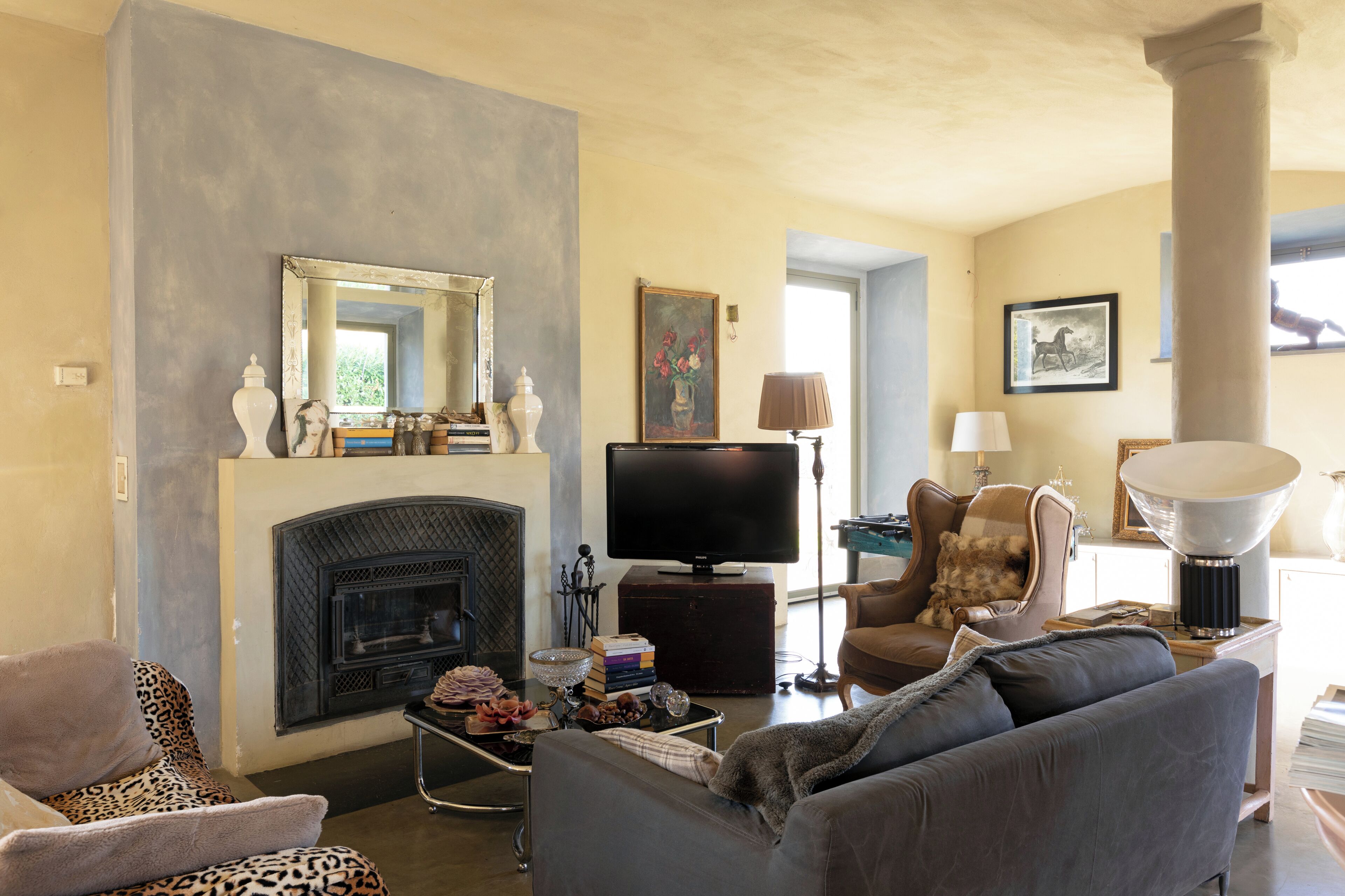 Una sala de estar con chimenea, televisor, sofá y sillón.