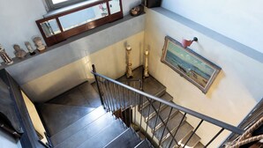 A staircase with a metal railing, a wooden cabinet with glass doors, and a framed painting on the wall. - CASA DELLE VIOLE (Fornovo di Taro)
