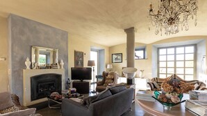 A living room with a fireplace, a sofa, a television, and a chandelier. - CASA DELLE VIOLE (Fornovo di Taro)