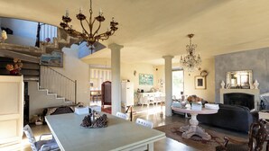 A spacious living area with a dining table, chairs, a chandelier, and a fireplace. - CASA DELLE VIOLE (Fornovo di Taro)