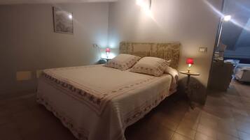 Un dormitorio con una cama grande, dos mesitas de noche con lámparas, un cabecero y un cuadro enmarcado en la pared.