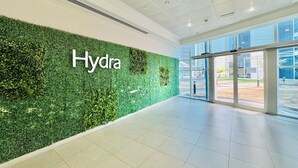 Un intérieur moderne avec un mur vert portant l’inscription « Hydra », de grandes fenêtres et un sol carrelé.