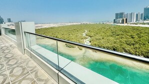 Un bâtiment moderne doté d’un balcon en verre qui offre une vue sur un paysage verdoyant et un ciel bleu azur.