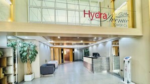 Un hall d’entrée spacieux comprenant un comptoir d’accueil, un espace salon et une grande plante en pot.