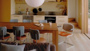 A modern kitchen with a dining area, featuring a large table, chairs, and a hanging light fixture. - Hidden Spring Beach S (Spring Beach)