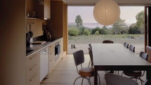 A modern kitchen with a dining area, large windows, and a view of the outdoors. - Hidden Spring Beach S (Spring Beach)