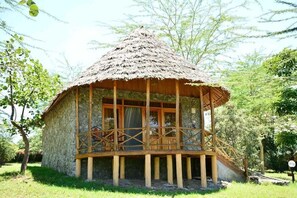 Una capanna con tetto di paglia, un balcone in legno e pareti di pietra.