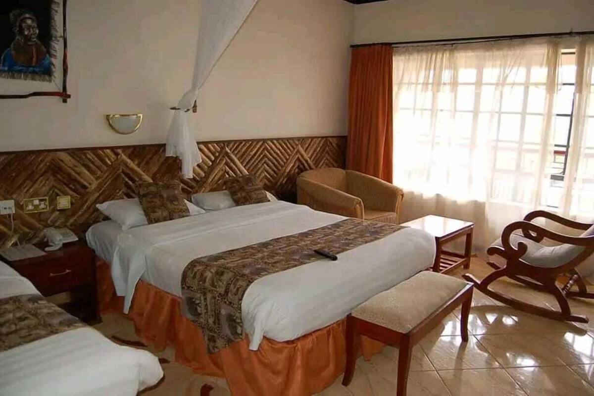 A hotel room with a large bed, a bedside table, a chair, and a window with curtains.