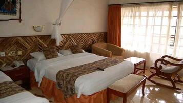 Una habitación de hotel con una cama grande, una mesita de noche, una silla y una ventana con cortinas.