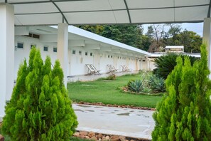 Un espacio al aire libre cubierto con un edificio blanco, césped verde y plantas en macetas.