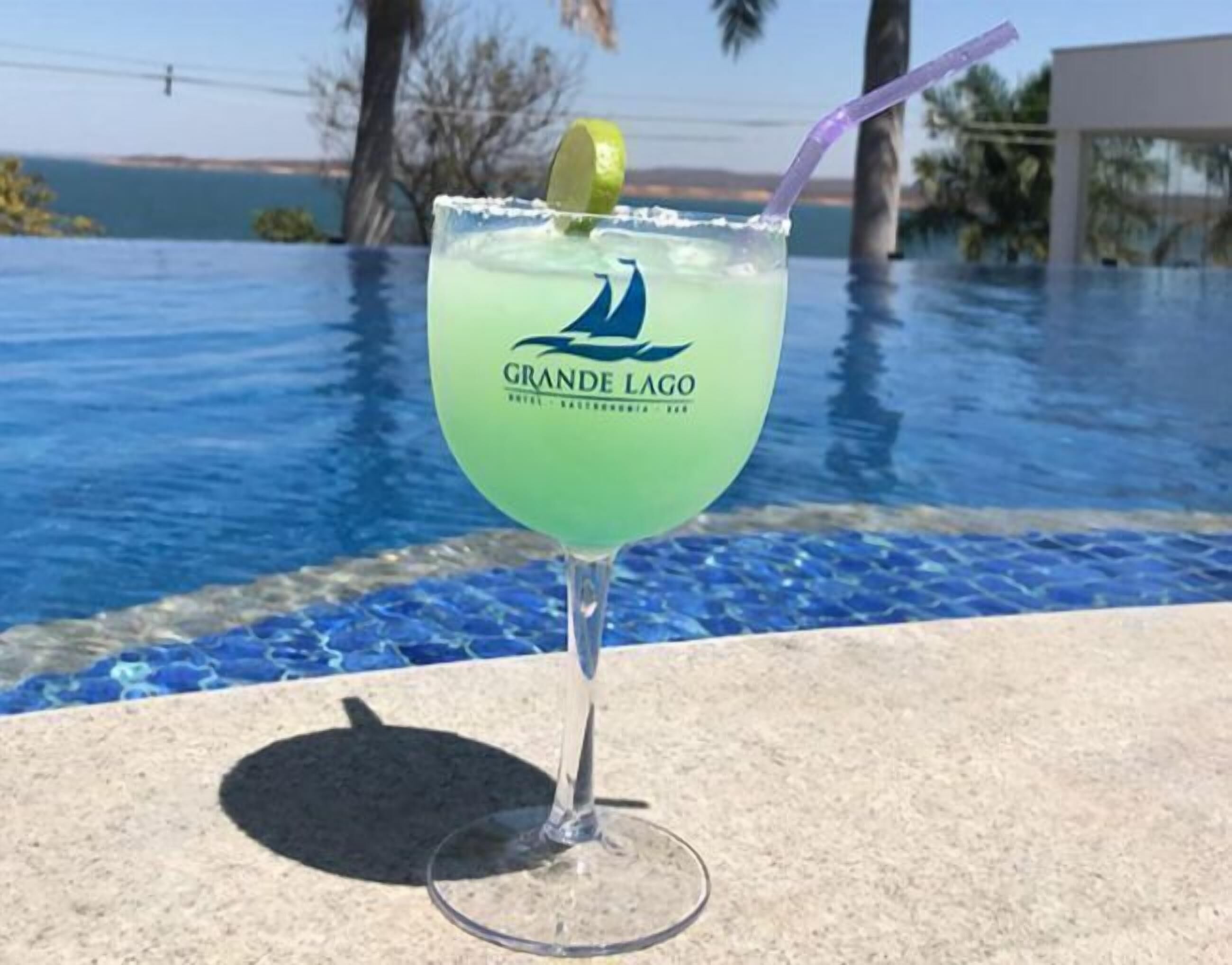 Ein A Grande Lago Cocktail mit Limettenscheibe vor einer Pool-Kulisse.