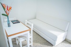 Un sofá blanco y una mesita pequeña con un libro y un jarrón de flores.