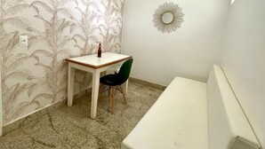 A small room with a patterned wallpaper, a round mirror, a table with a bottle, and a chair. - Grande Lago Hotel Gastronomia Bar (Três Marias)