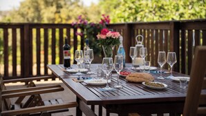 An outdoor wooden table set for a meal with wine glasses, plates, and a loaf of bread. - Laftira's Sea View Home (Stegna)