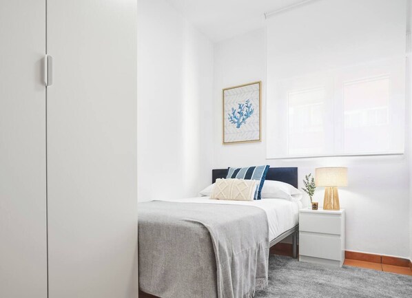 Une chambre à coucher avec un lit, une table de chevet, une lampe et un tableau encadré au mur.