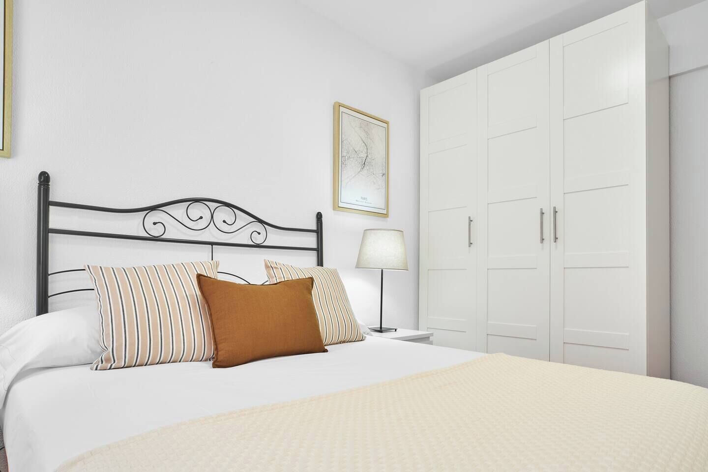 Un dormitorio con una cama, una mesita de noche, una lámpara y un armario.