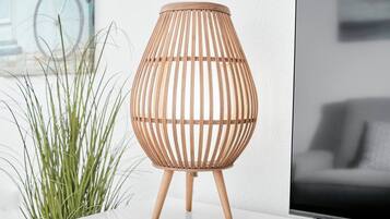 A wicker lamp with a cylindrical shape and a wooden base on a white surface.