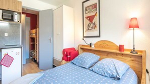 A bedroom with a bed, a small fridge, a microwave, and a wooden wardrobe. - Studio in Chamrousse Near Ski Resort (Chamrousse)