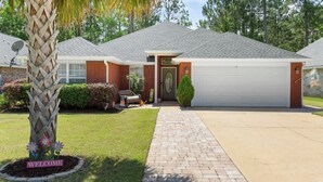 A two-story house with a brick facade, a garage, and a well-maintained lawn.
