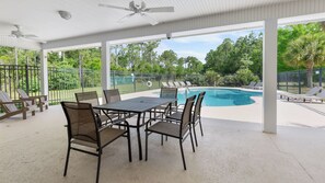 A covered outdoor area with a pool, chairs, and a table.