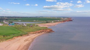 Un paisaje costero con una playa arenosa, un pequeño asentamiento con casas y vistas al mar.