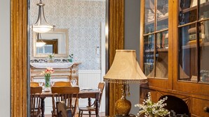 Een houten eettafel met stoelen, een lamp en een kast met glazen deuren.
