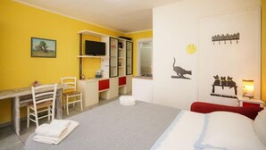 Quarto com cama, escrivaninha, cadeira, guarda-roupa e televisão.