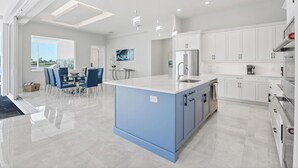Een moderne keuken met witte kasten, een blauw kookeiland en roestvrijstalen apparatuur.