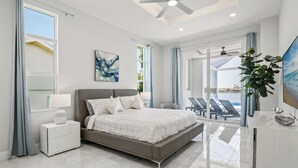Een moderne slaapkamer met een groot bed, een nachtkastje, een bureau en uitzicht op het omliggende landschap.