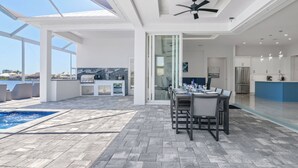 Een moderne keuken met een groot eiland, een eethoek met een tafel en stoelen, en een zwembadgedeelte met een whirlpool.