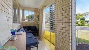 Un balcón con zona de estar, una pequeña mesa con un plato decorativo y una ventana con vistas al exterior.