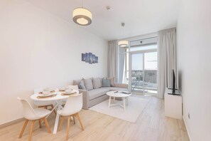 A modern living room with a sofa, dining table, chairs, and a TV.