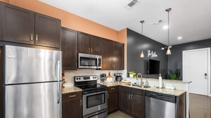 A modern kitchen with dark cabinets, stainless steel appliances, and a granite countertop. - Beautiful Condo for 4, Mins to Nashville Nightlife (Nashville)