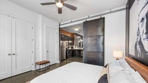 A modern hotel room with a large bed, a ceiling fan, and a view into the kitchen area. - Beautiful Condo for 4, Mins to Nashville Nightlife (Nashville)