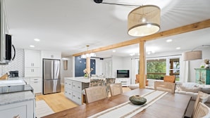 A modern kitchen with white cabinets, stainless steel appliances, and a dining area with a wooden table and chairs.