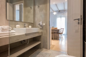A modern bathroom with a large mirror, a sink, and a towel rack. - Michael Zeppos Studios, Naousa (Paros)