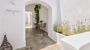A reception area with a stone floor, white walls, and a potted plant. - Michael Zeppos Studios, Naousa (Paros)