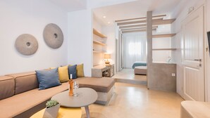 A modern living room with a sofa, a coffee table, and a lamp. There is a door leading to another room. - Michael Zeppos Studios, Naousa (Paros)
