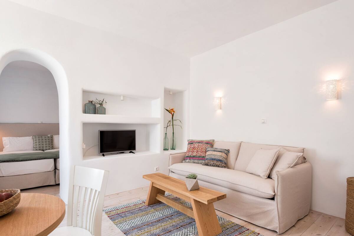 Ett modernt vardagsrum med en soffa, en tv, ett soffbord och en matplats med en stol och en fruktskål.