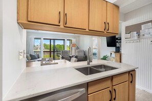 A modern kitchen with wooden cabinets, a double sink, and a view to a balcony with seating. - Relaxing 9th Hole View - For 6! (Branson)